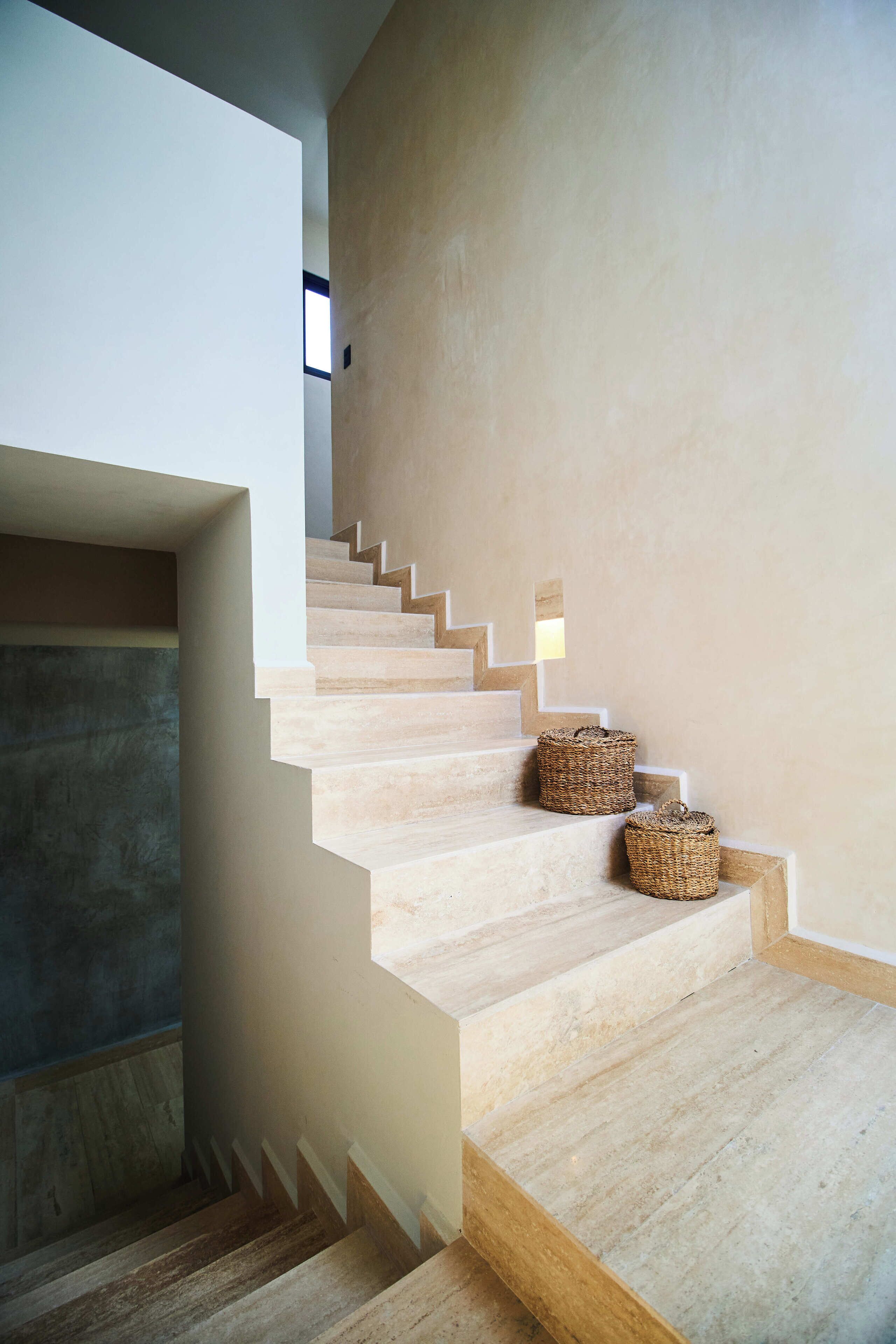 A modern staircase with wooden steps and two woven baskets at the landing.