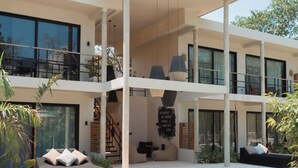 A modern two-story house with a swimming pool, outdoor seating, and a staircase leading to the upper level. - BT Homes - Wellness Jungle (Tulum)