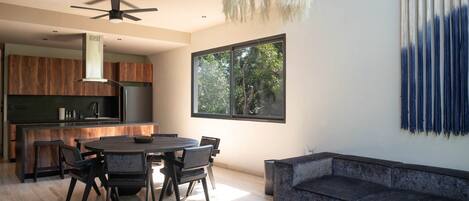 Una cocina moderna con armarios de madera oscura, una isla central y un comedor con una mesa redonda y sillas.