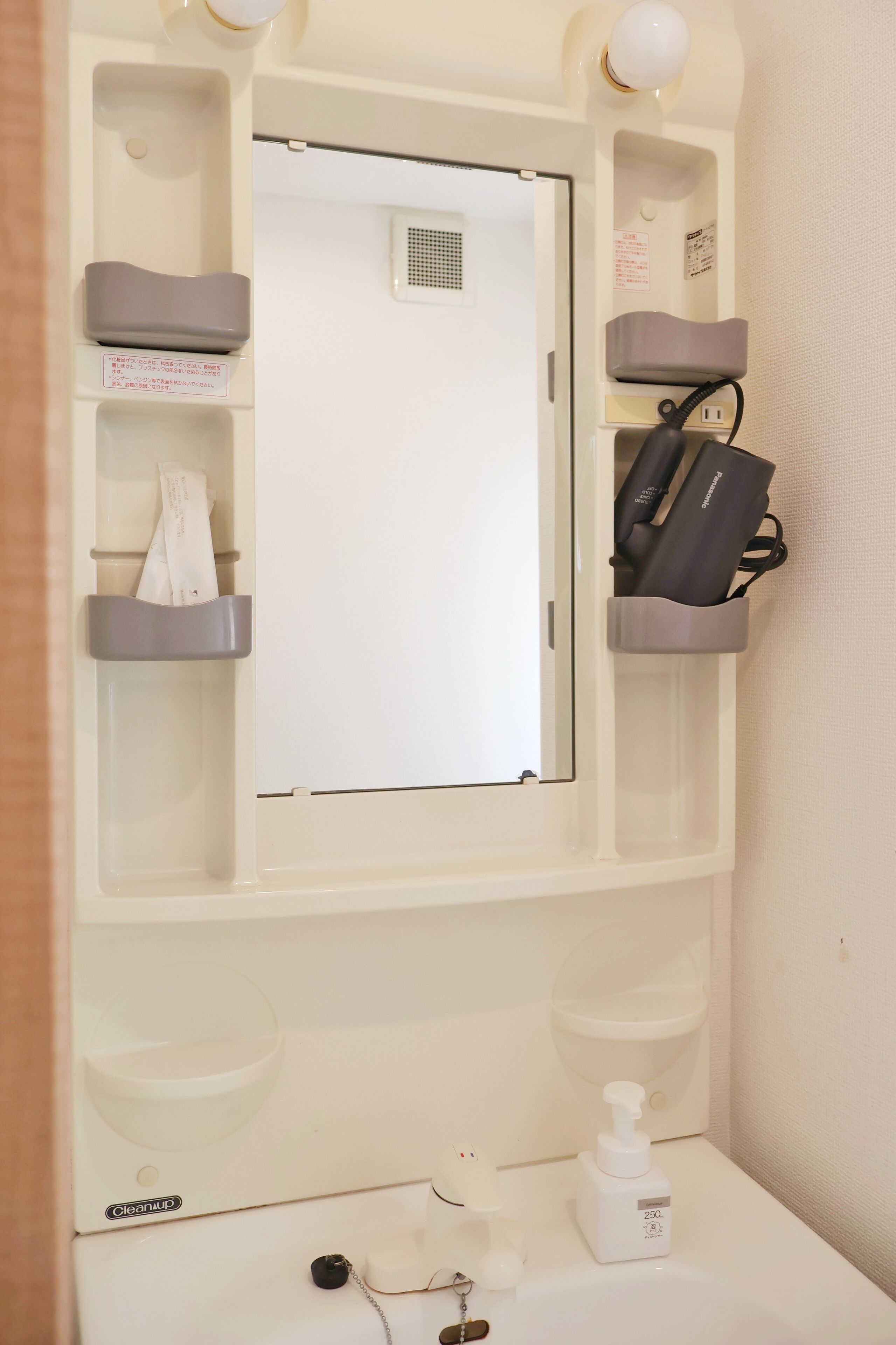 A bathroom with a mirror, towel rack, and a soap dispenser.