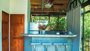 A kitchen with a bar area, wooden doors, and a ceiling fan. - 5 min to beach-private pool-great for couples (Dominicalito)