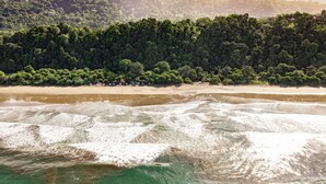 A beach with waves, a forested hill, and a row of beach huts. - 5 min to beach-private pool-great for couples (Dominicalito)