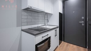 A modern kitchen with a built-in oven, a sink, and a stainless steel range hood. - Arama Nilie Hospitality MGMT (Thessaloniki)