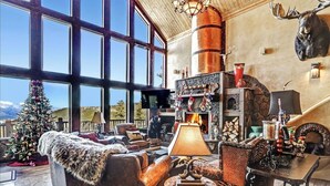 A cozy living room with a fireplace, leather furniture, and a Christmas tree. - Spacious, Custom Built, Luxury Home Cabin with Hot Tub, Stunning Views,  (Angel Fire)