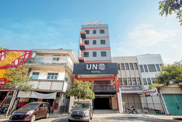 A hotel with a prominent 'UNO HOTEL' sign, a visible entrance, and a parked car in front. - Hotel O Genteng Near Genteng Market Formerly Uno Hotel (Surabaya)