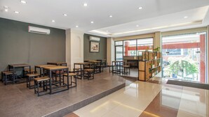 Un interior moderno con varias mesas y bancos, un techo con iluminación empotrada y un ventanal con vistas al exterior.