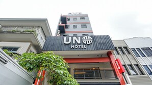 Un hotel con un llamativo letrero que dice 'UN HOTEL', diseño arquitectónico moderno y un balcón con plantas visibles.