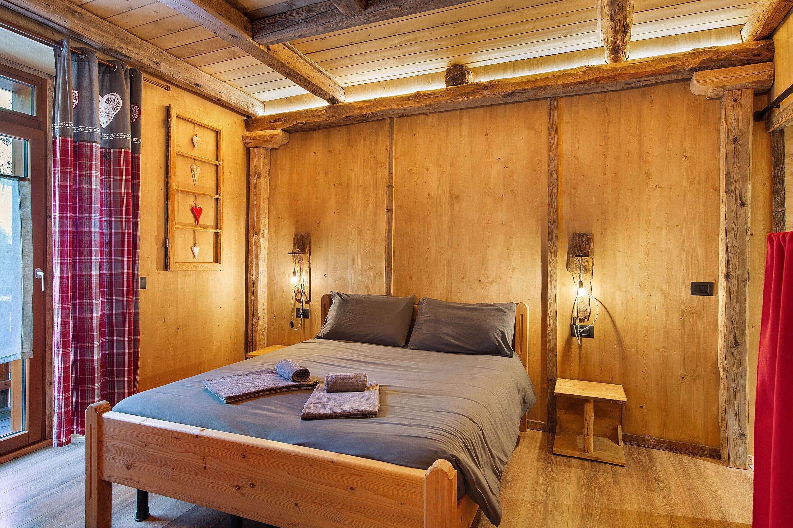 Een houten kamer met een bed, een plank met decoratieve objecten en een klein nachtkastje.