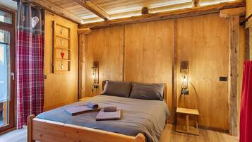 Een houten kamer met een bed, een plank met decoratieve objecten en een klein nachtkastje.