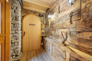 Un intérieur en bois avec un mur en pierre, une porte en bois et un banc.