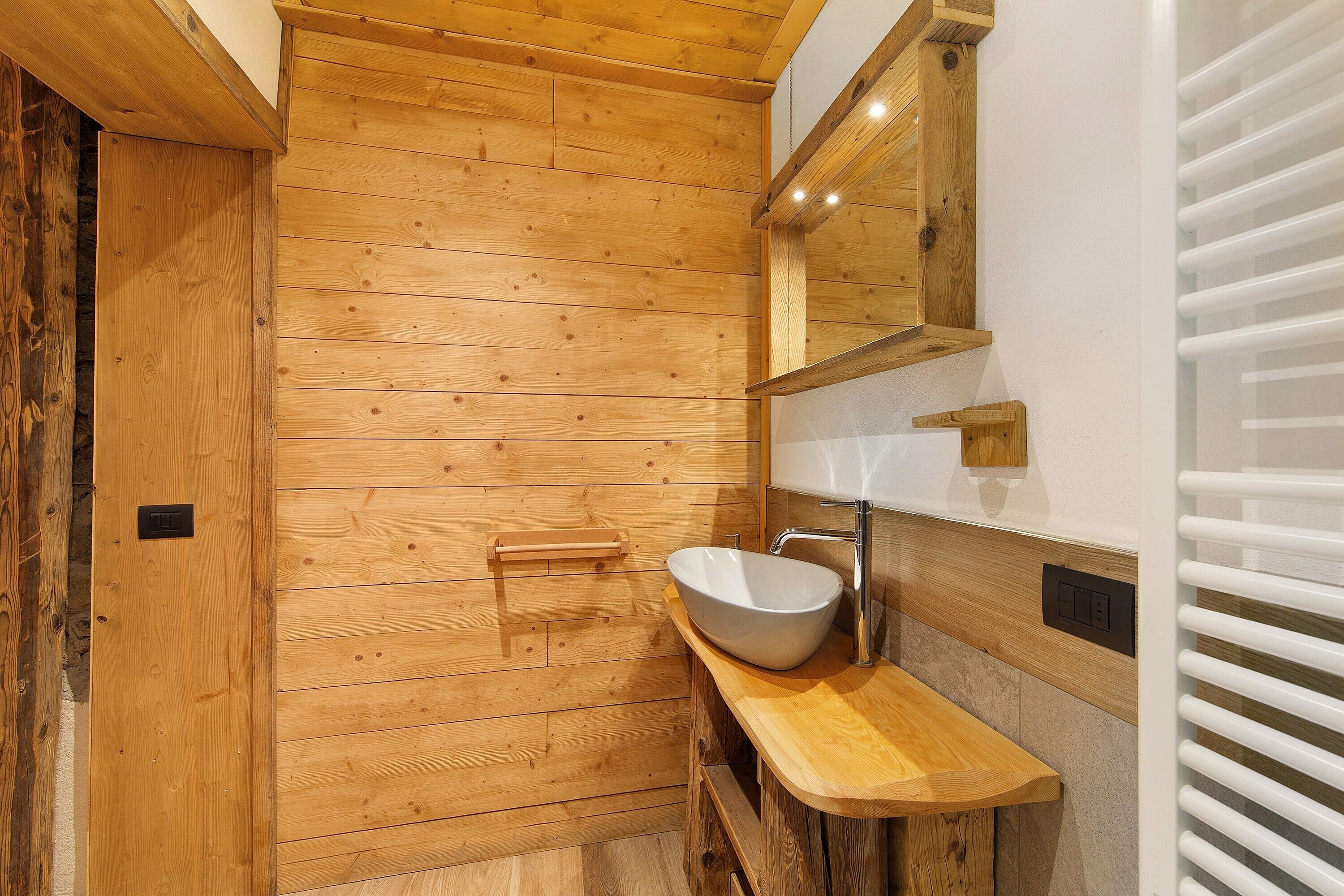 A wooden-paneled bathroom with a wooden vanity, a white sink, and a mirror.