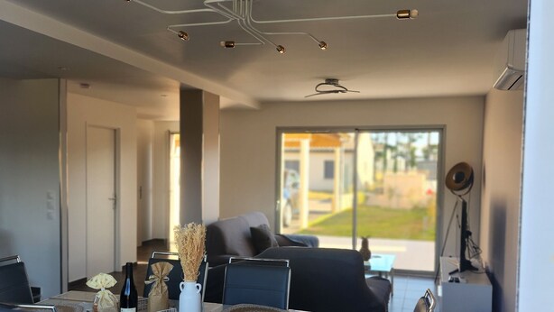 A modern dining area with a white table set for six, black chairs, and a ceiling light fixture.