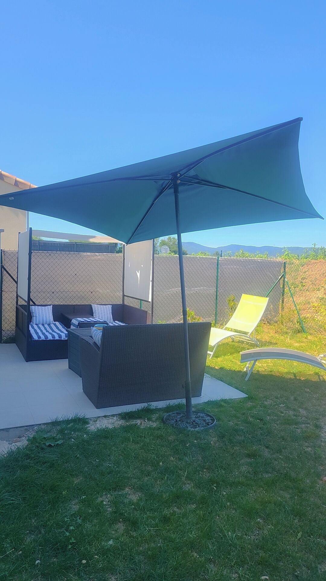 An outdoor seating area with a large umbrella, a sofa, and a chair.