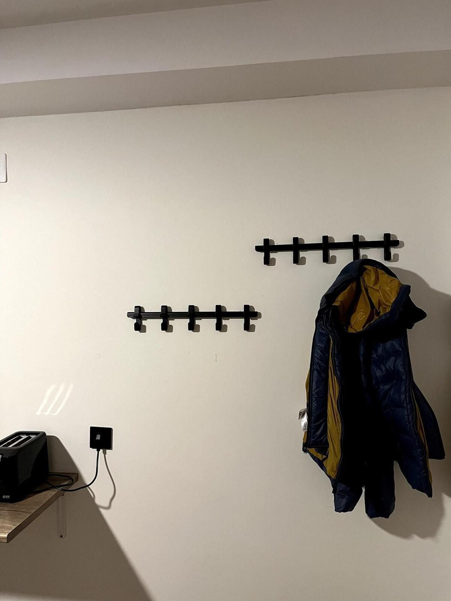 A wall-mounted coat rack with a jacket hanging on it.