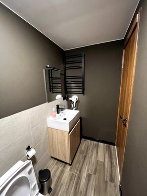 A compact bathroom with a toilet, sink, and mirror.