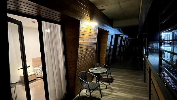 A corridor with wooden flooring, a glass door leading to a room with a bed and a table, and two chairs near the door. - Gudauri - Apartment - Sleeps 4 - Pool - Parking (Kazbegi)