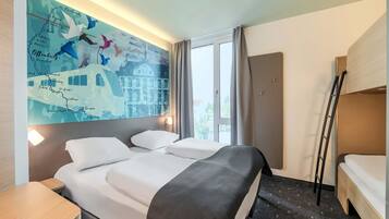 Ein Hotelzimmer mit einem großen Bett, einem Schreibtisch, einer Karte an der Wand und einem Fenster mit Vorhängen.