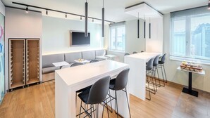Eine moderne Küche mit Kochinsel, Barhocker, Esstisch und einem an der Wand montierten Fernseher.