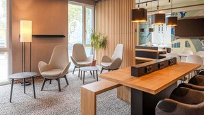 A modern office space with a long wooden table, several white chairs, and a large window providing natural light.