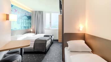 Ein Hotelzimmer mit zwei Betten, einem Schreibtisch und einem Stuhl. An der Wand hängt ein Bild und es gibt ein Fenster mit Vorhängen.