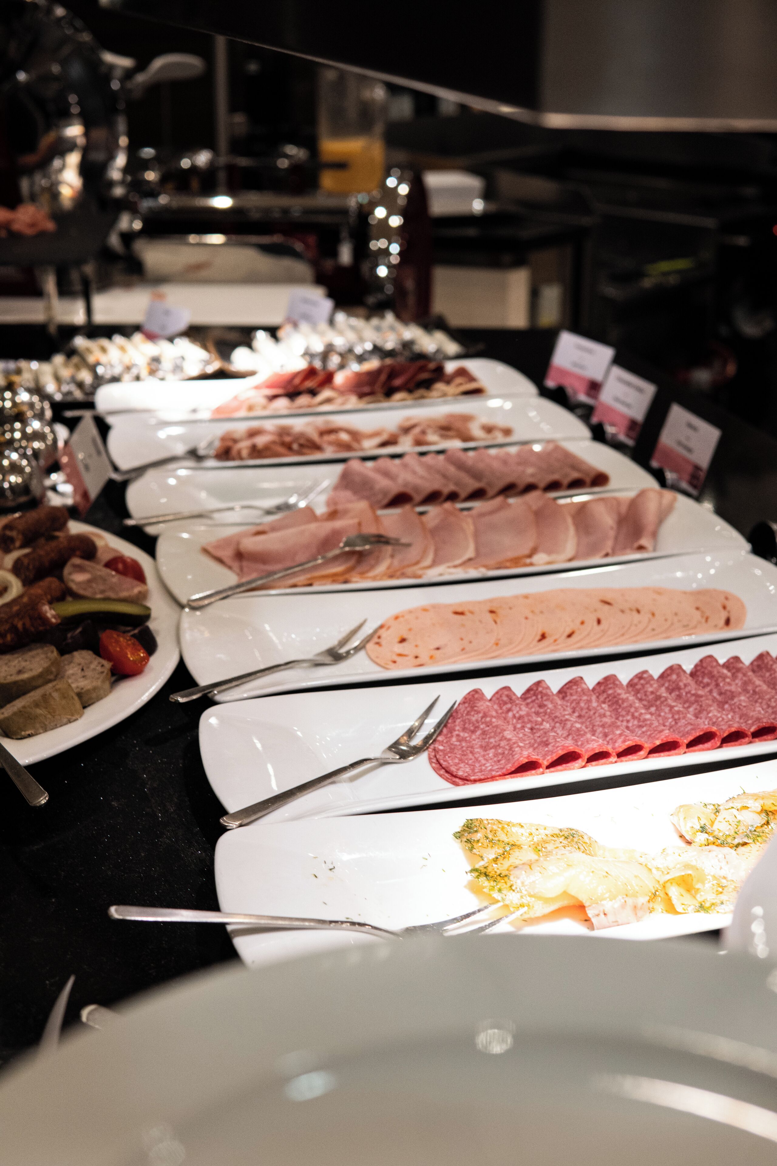A buffet with various food items including meats and cheeses.