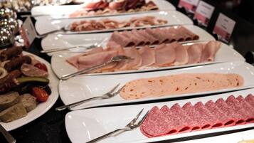 A buffet with various food items including meats and cheeses.