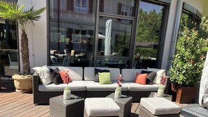An outdoor seating area with a sofa and ottomans, a palm tree, and a potted plant.