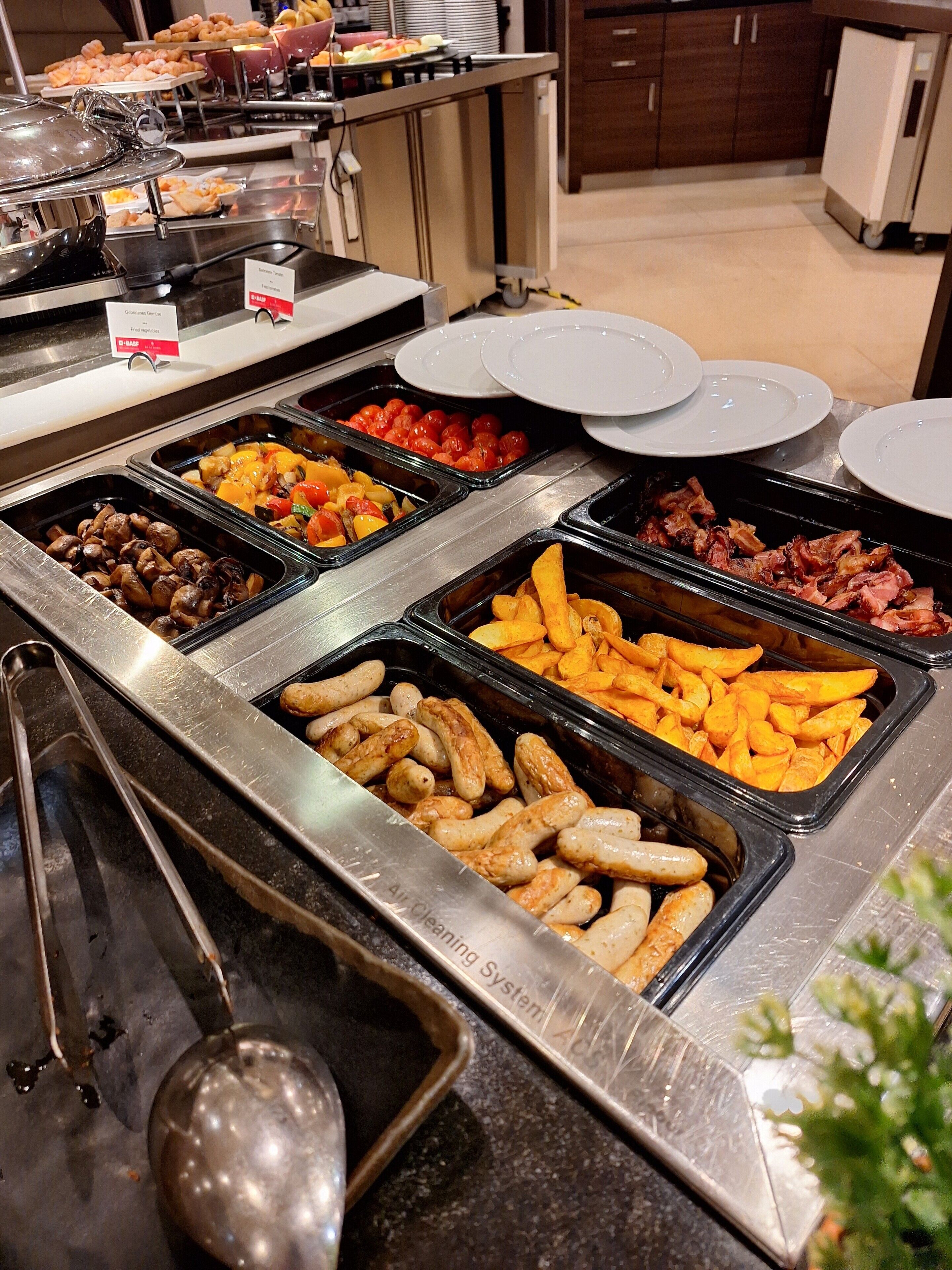 Un buffet proposant une variété de plats, notamment des saucisses, du poulet et des légumes.