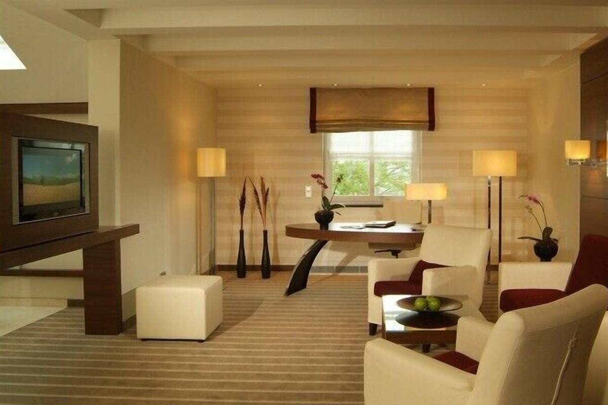 A modern living room with a flat-screen TV, a dining area with a table and chairs, and a red sofa.