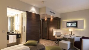 A modern hotel room with a bed, a desk, a chair, and a TV.