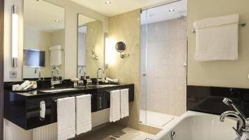 A modern bathroom with a black countertop, two sinks, a large mirror, a bathtub, and a glass shower enclosure.