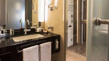 Un baño moderno con encimera negra, un espejo grande, un perchero y una puerta de ducha de cristal.