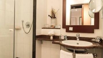 A modern bathroom with a glass shower enclosure, a large mirror, and a sink with a towel rack.