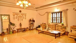 A cozy living room with a wooden sofa, a coffee table, and a chandelier. - Dragonfly Goa (Arambol)
