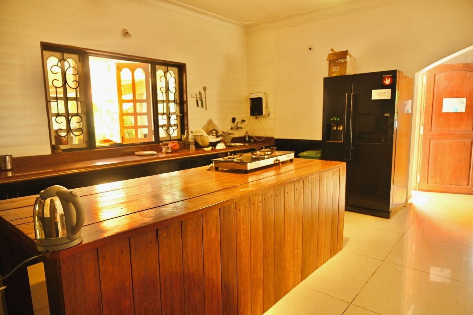 A kitchen with a wooden island, a black refrigerator, and a window with decorative glass.