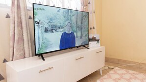 Een flatscreen televisie op een witte tv-meubel, met een afstandsbediening ernaast.
