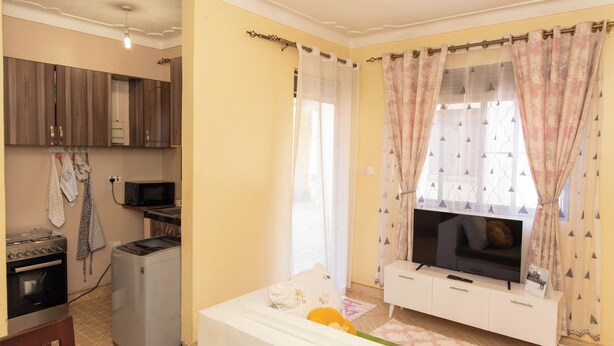 Een ruimtelijke woonruimte met een kitchenette, een televisie en een eethoek.