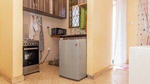 Een compacte keuken met een ingebouwde oven, een magnetron en een koelkast.
