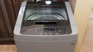 Een voor aanzicht van een compacte, grijze wasmachine met voorlader, een digitaal display en bedieningspaneel.