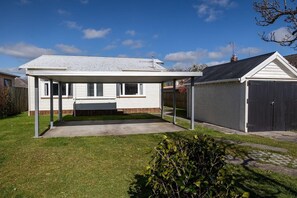 A single-story house with a covered patio, a fenced yard, and a garage.
