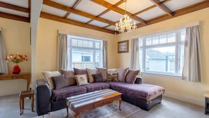 A cozy living room with a sectional sofa, a wooden coffee table, and a chandelier.