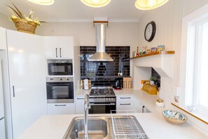 A modern kitchen with white cabinetry, stainless steel appliances, and a black tiled backsplash.