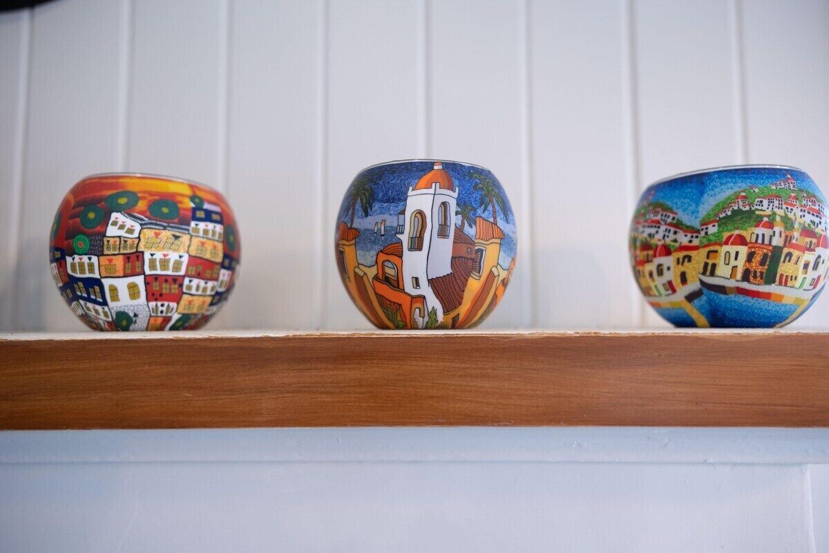 Tres cuencos de cerámica con diferentes diseños pintados sobre una estantería.