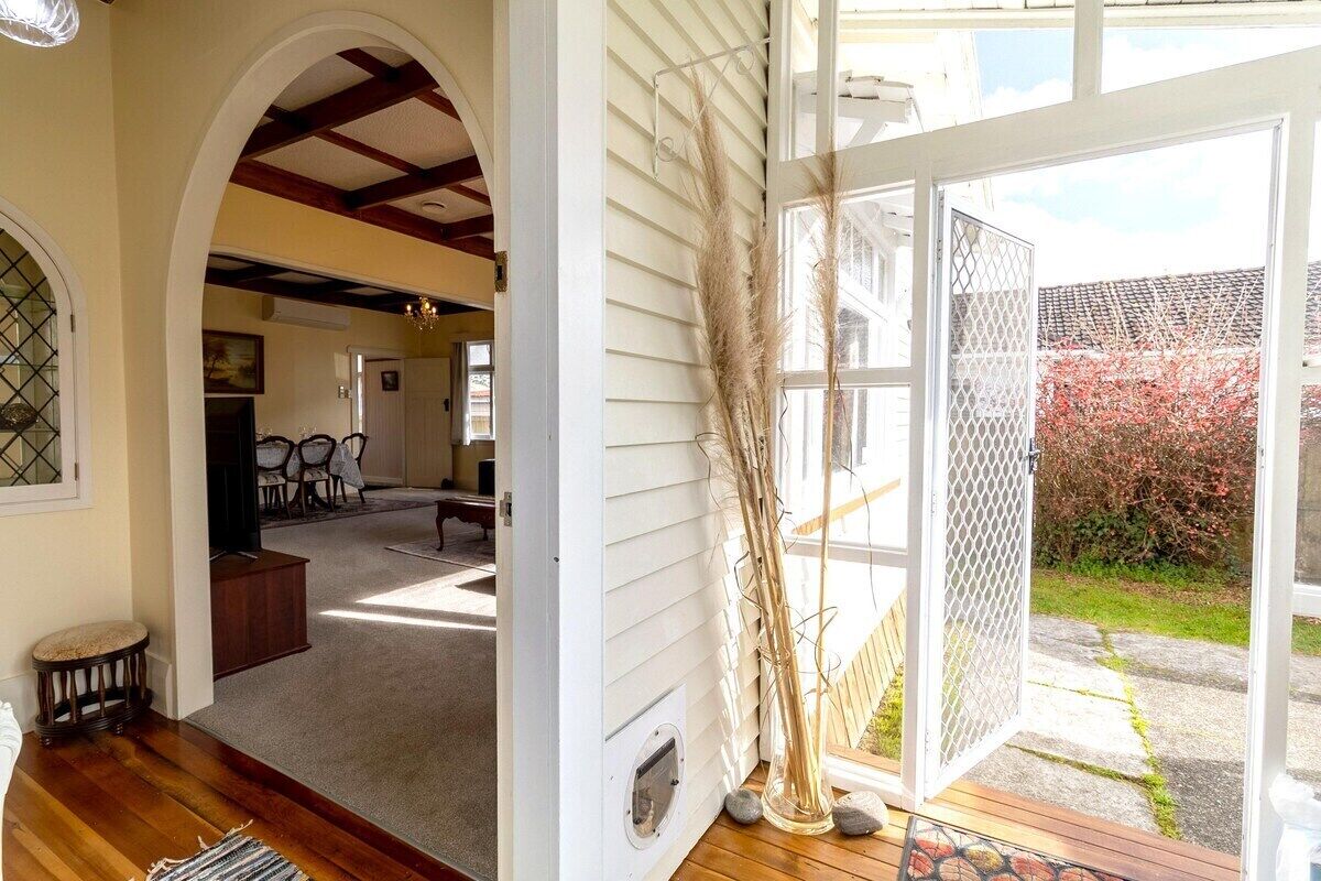 A room with a wooden floor, a white door, and a view of a garden.