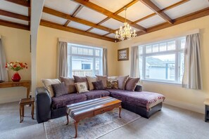 A living room with a sectional sofa, a wooden coffee table, and a chandelier.