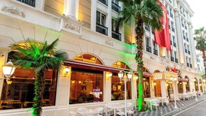 A hotel with outdoor seating, palm trees, and a checkered floor. - Baron Hotel & Spa (Istanbul)
