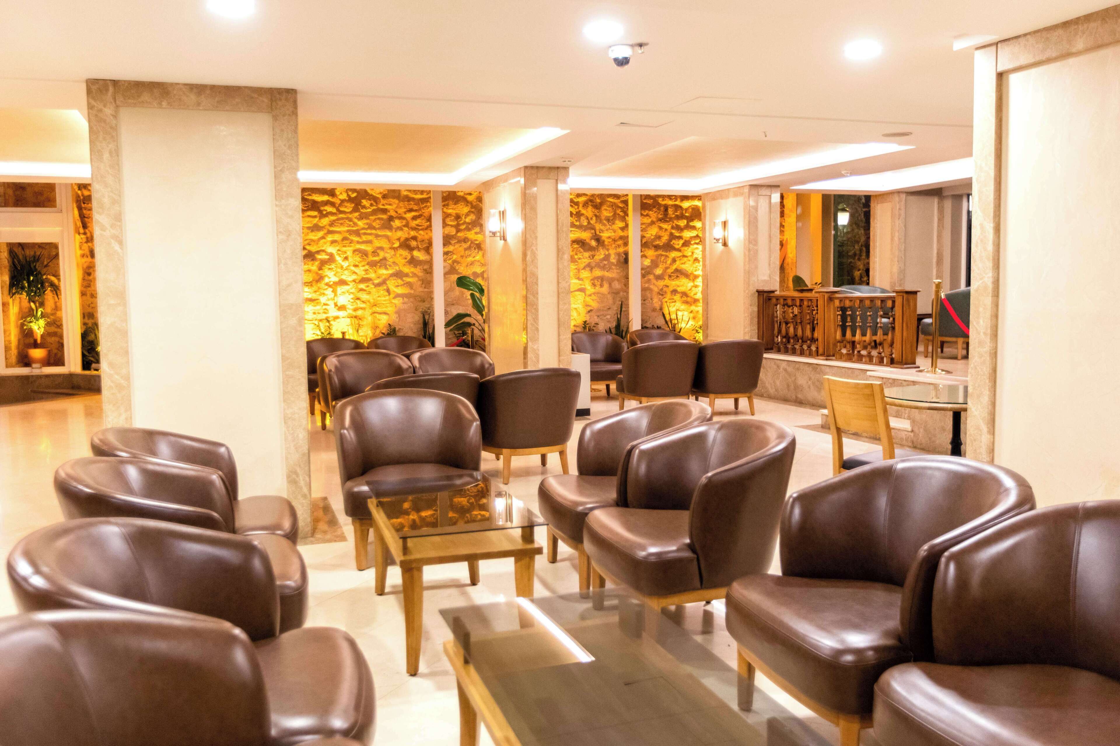 Un vestíbulo con sillones de cuero, un mostrador de recepción y una pared de piedra.