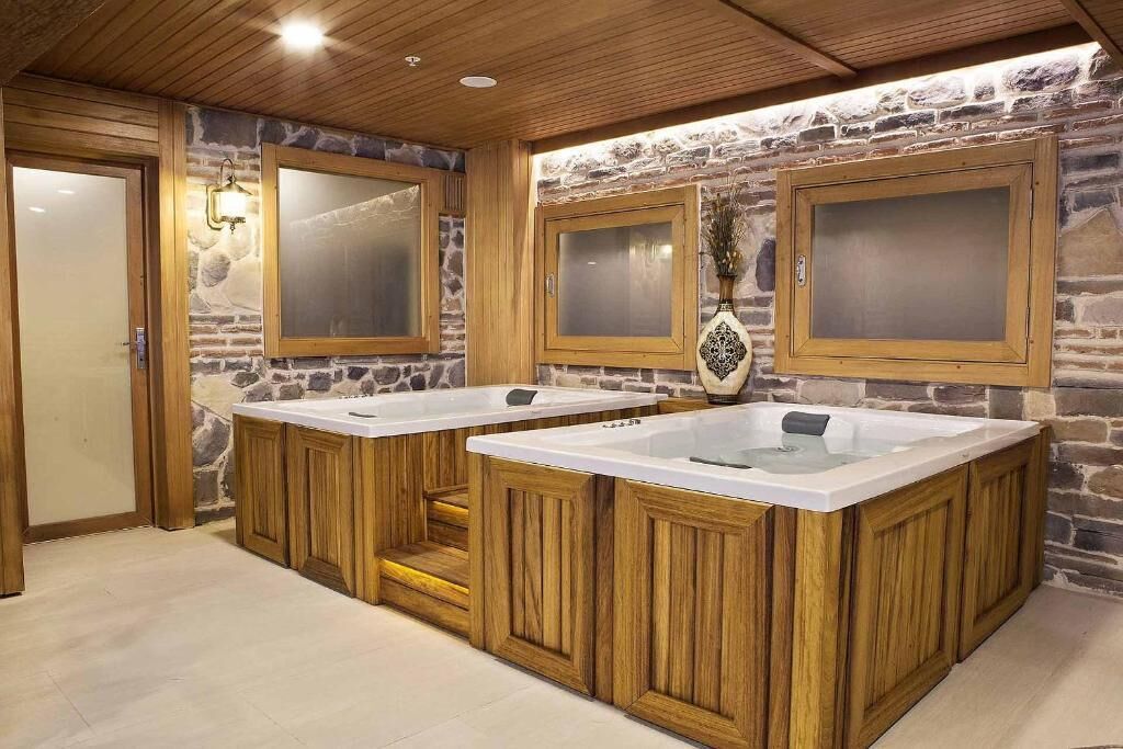 Ein Badezimmer mit zwei Waschtischen aus Holz, Steinwänden und einer Holzbalkendecke.
