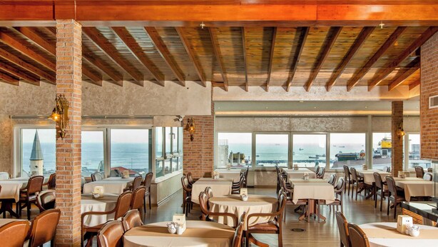 A restaurant with wooden beams, brick walls, and tables with white tablecloths. - Baron Hotel & Spa (Istanbul)