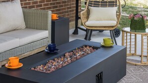 Une terrasse dotée d’un foyer, de meubles en osier et d’un barbecue.